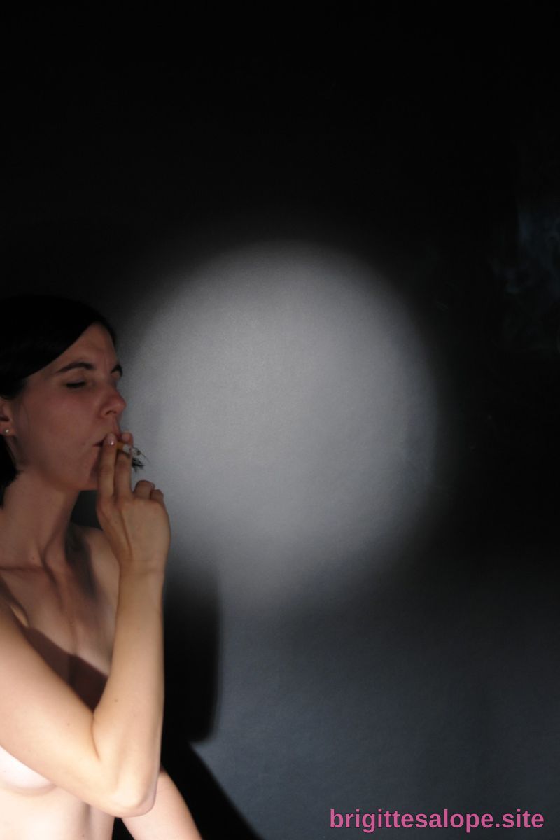 Femme en noir fumant dans l'obscurité — Brigitte la Salope