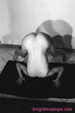Musclé et nu, assis sur un tapis noir, lumière intense sur le dos — Brigitte la Salope