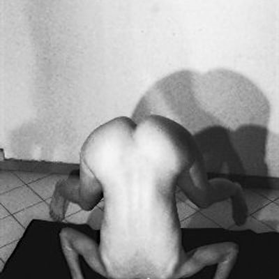 Musclé et nu, assis sur un tapis noir, lumière intense sur le dos — Brigitte la Salope